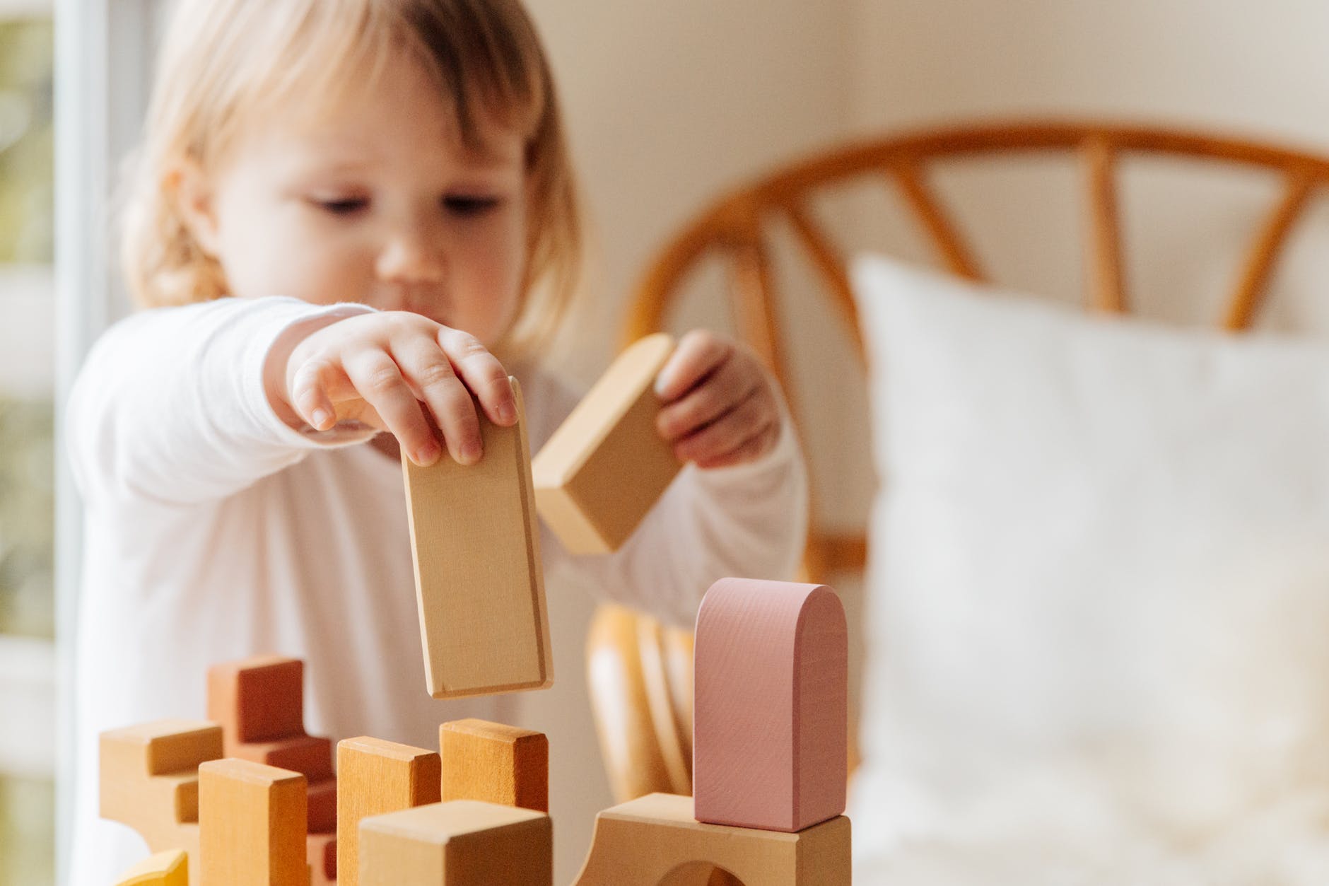 little girl playing with wooden blocks at home
